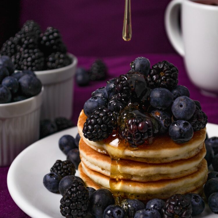 Pancakes with black berries on white ceramic plate 3780469