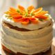 A carrot cake with white icing and carrots on top of it