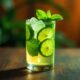 Mojito cocktail glass with ice pieces, fresh mint leaves and lime slices with tube